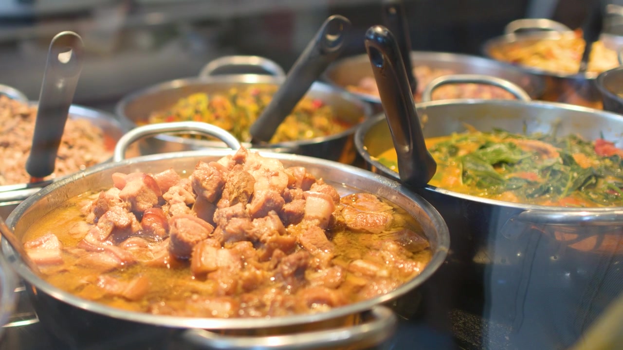 Primo piano di stufato di maiale tradizionale della Thailandia del Nord e vari curry in un ambiente da caffetteria.