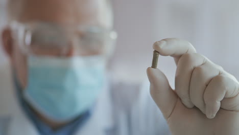 extreme close-up of scientist in the mask developer of the vaccine against coronavirus holds in his hands the green one. the doctor looks at the painkillers antiviral medication. vitamins. high quality 4k footage