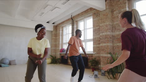 una alegre pareja negra bailando en clase con una instructora