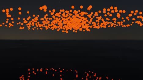 hundreds of sky lanterns floating upwards in the night sky