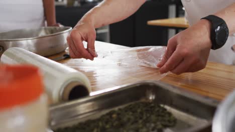 Caucasian-female-chef-teaching-diverse-group-preparing-dishes-and-smiling