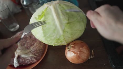 pov of testing cabbage firmness with spoon and fork, finger tapping, listening for sound in a kitchen setup, hand-held shot