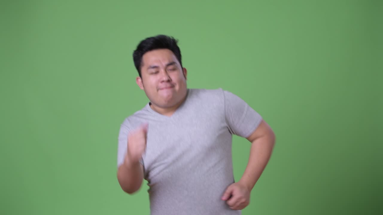 초록색 배경에 젊은 잘생긴 과체중 아시아인