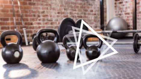 Animation-of-white-triangles-spinning-over-kettlebells-and-weights-in-gym