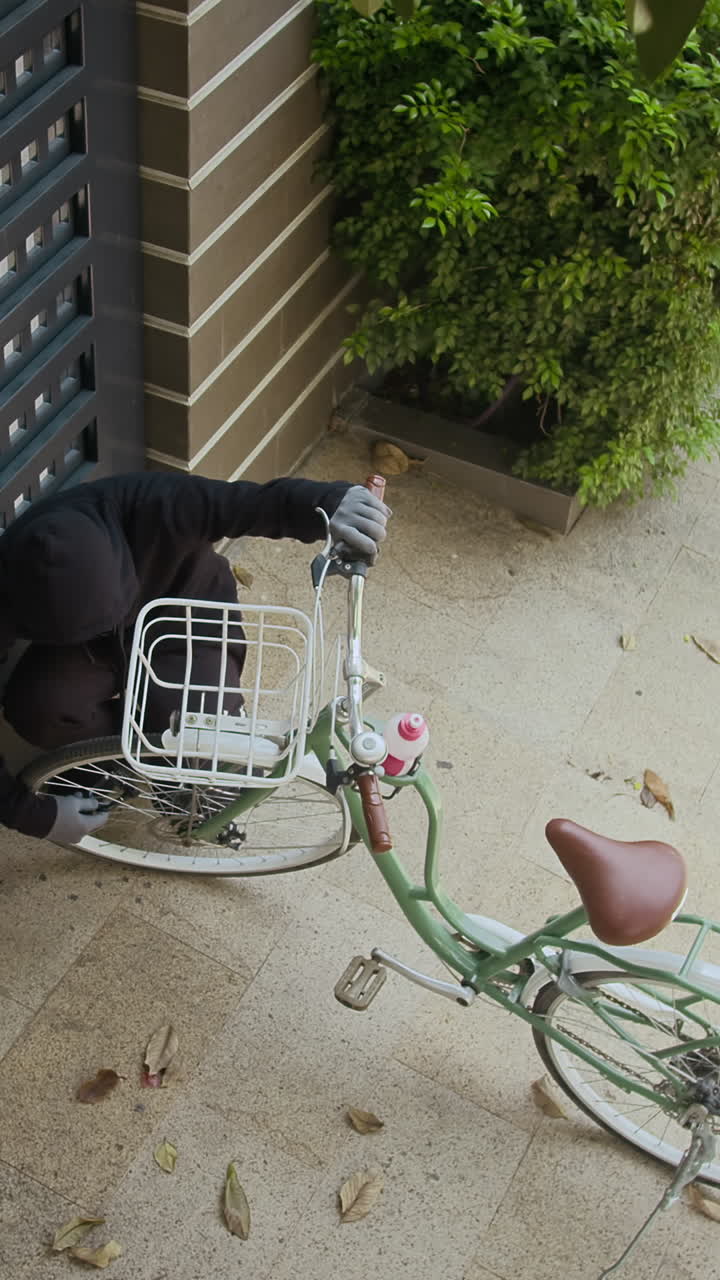 Vertical of Burglar Stealing Bicycle near Gate