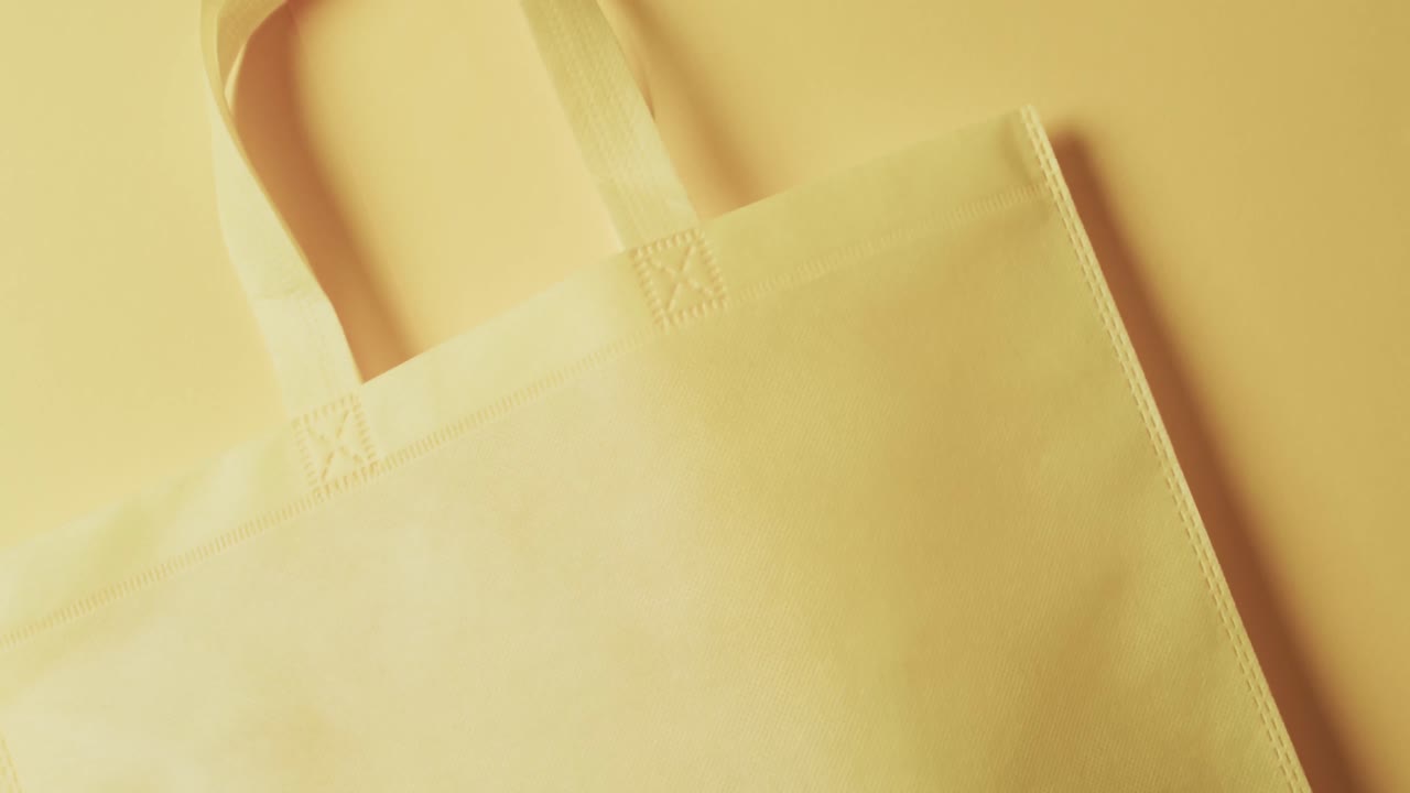 노란색 배경에 복사 공간이 있는 노란색 캔버스 가방의 비디오