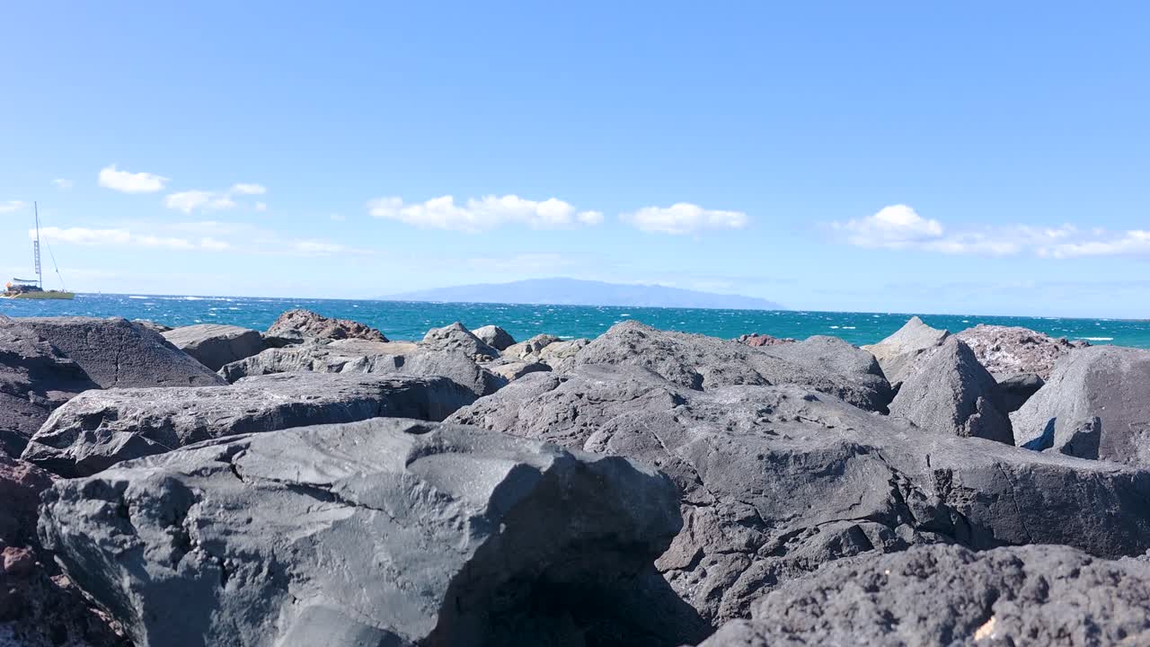 青い空と穏やかな海の下をボートが航行する、ビーチからの島の眺め。