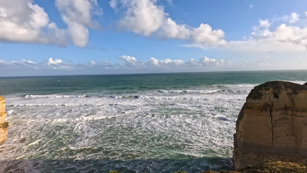 밝은 하늘 아래 절벽에 부히는 파도