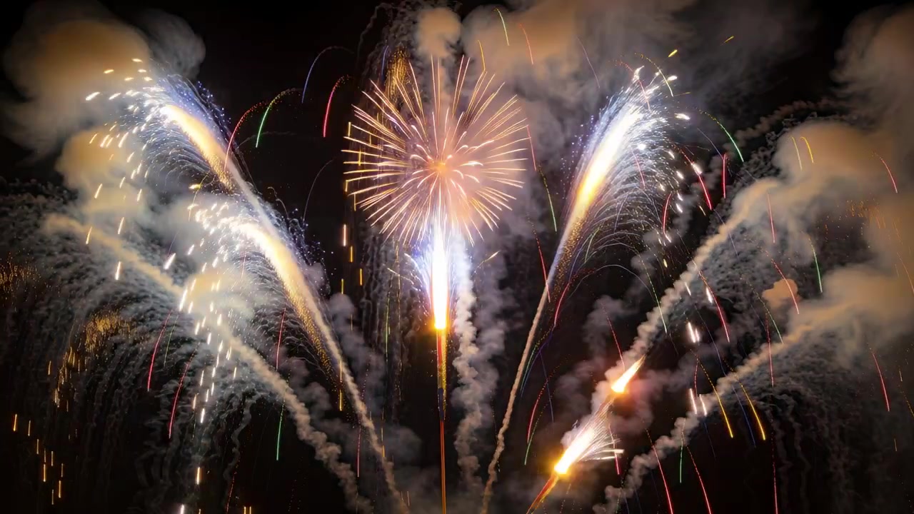 Lancio di fuochi d'artificio luminosi da una base di lancio di notte, con proiettili aerei che formano archi a ventaglio e getti bianchi che si innalzano.