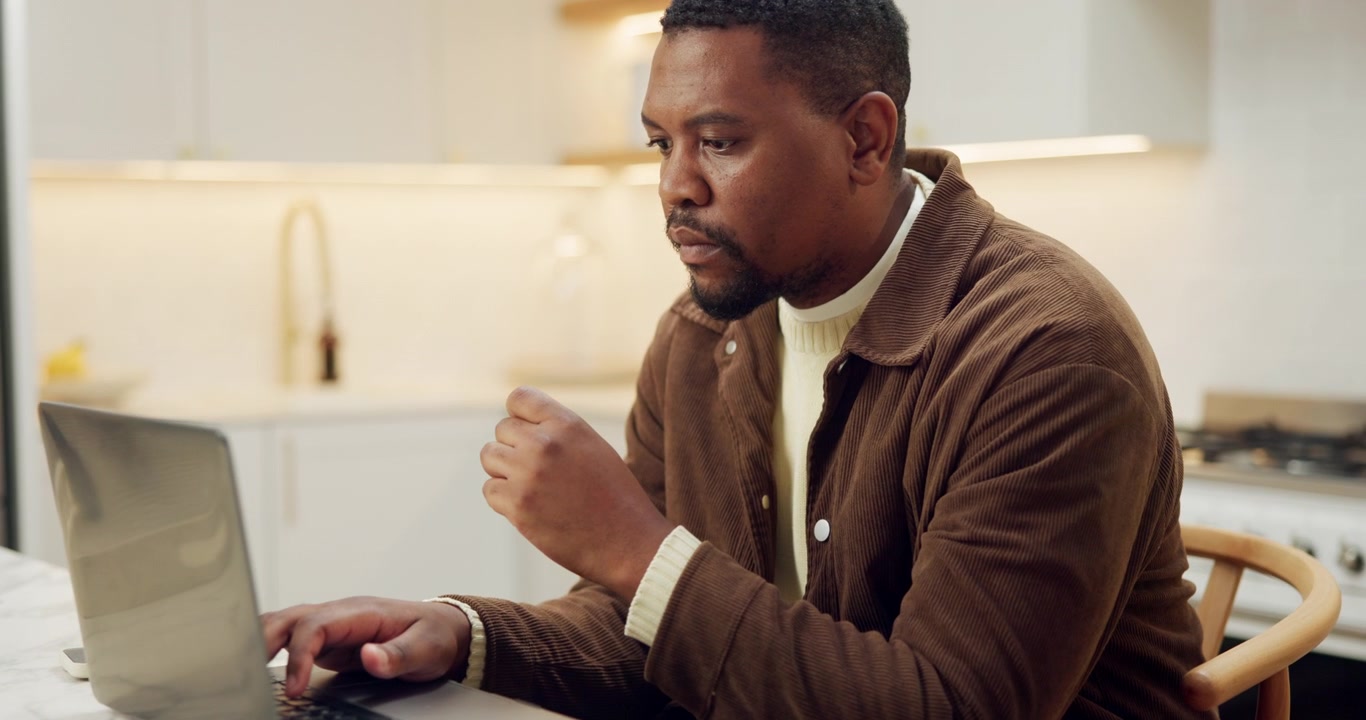 Focused Man Working on Laptop in Modern Kitchen