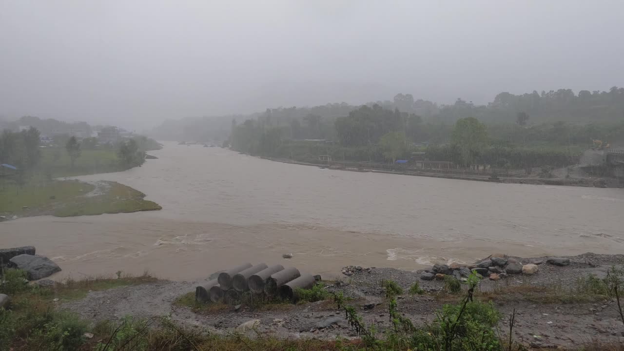 A high angle panning view of the raging flood waters in a river from a typhoon in India during the heavy rain in Nepal