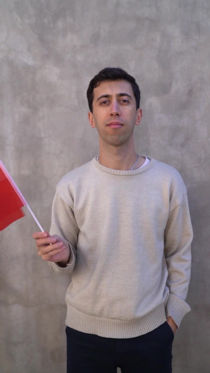 Rekaman vertikal seorang pria mengibarkan bendera Albania. Konsep patriotisme. Gerak lambat.