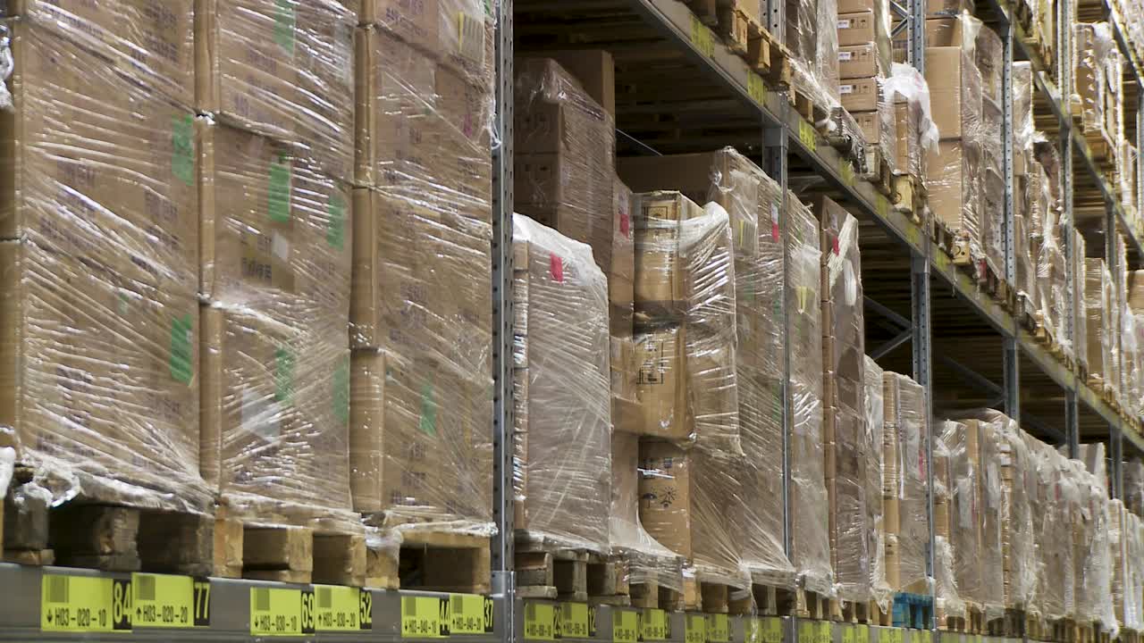 Rows of wrapped pallets stacked in a warehouse, showcasing logistics and storage, shallow focus