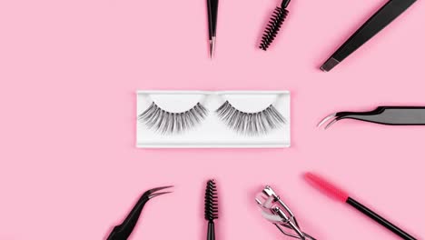 makeup accessories. fake eyelashes. tools for eye lash extensions on trendy pastel pink background. concept. eyelash curler, tweezers, brushes, mascara. cosmetic products. animation. beauty pattern.