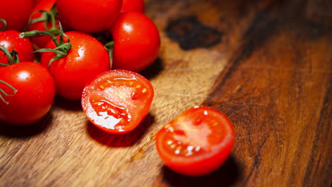 fotografía de mano de una mano masculina cortando un tomate rojo por la mitad en una tabla de cortar de madera