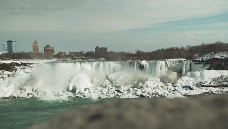 wide view of icy niagara falls in winter, reveal pan from behind wall