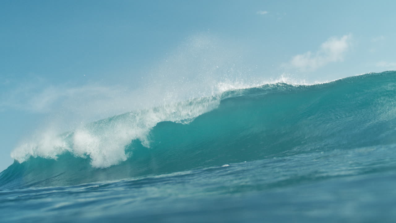 Wide of clear turquoise waves undulating gently under sunny skies