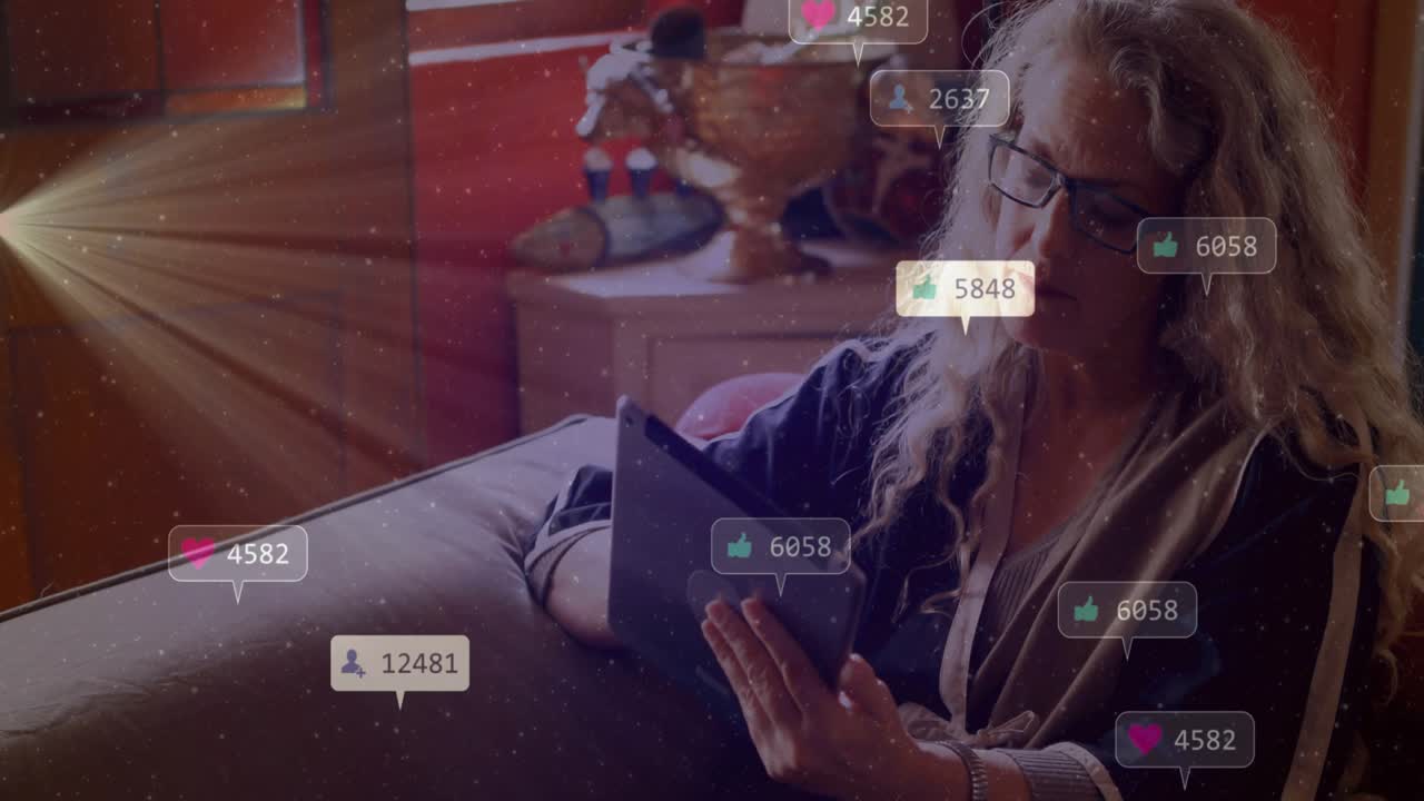 Mature woman tapping tablet on sofa creating filling social badges showing likes driving engagement