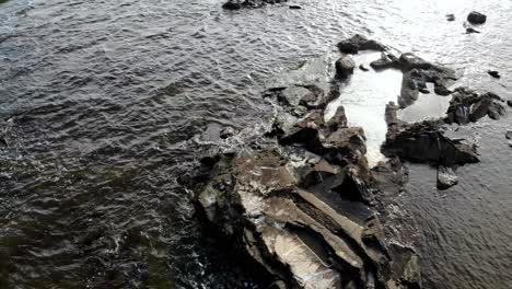 aerial view of stones in the sea with waves crashing on a sunny day at montevideo uruguay pier