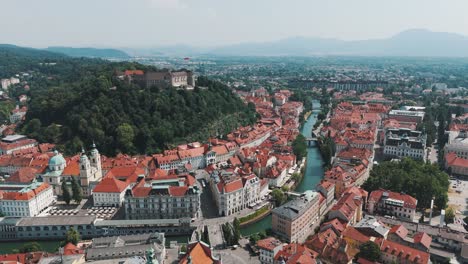 aerial drone fly historic european city next to clean water canal river in ljubljana old town with castle and prešeren square on a summer day