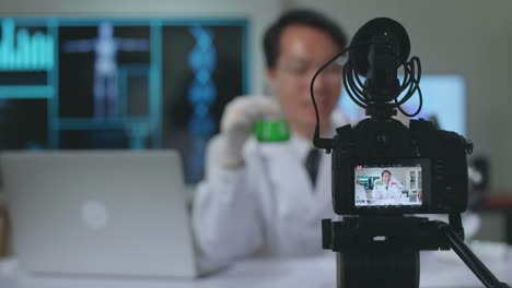 camera display of asian scientist researching in the laboratory with test-tube and speaking