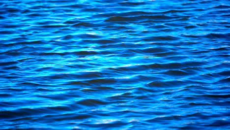 blue waves on the surface of a lake, sea or ocean in slow motion - background texture