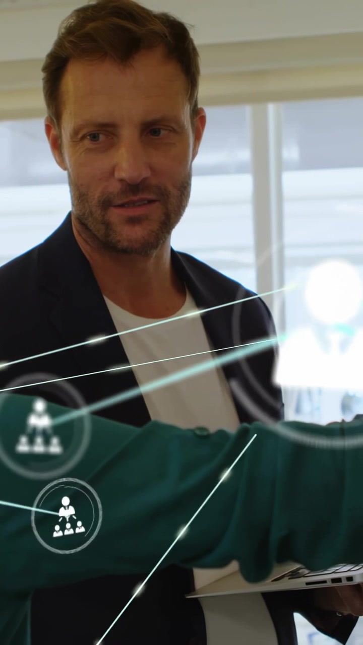 Video verticale: Uomo che digita sul laptop mentre un collega indica, con nodi di rete in crescita in sovrimpressione per il business.