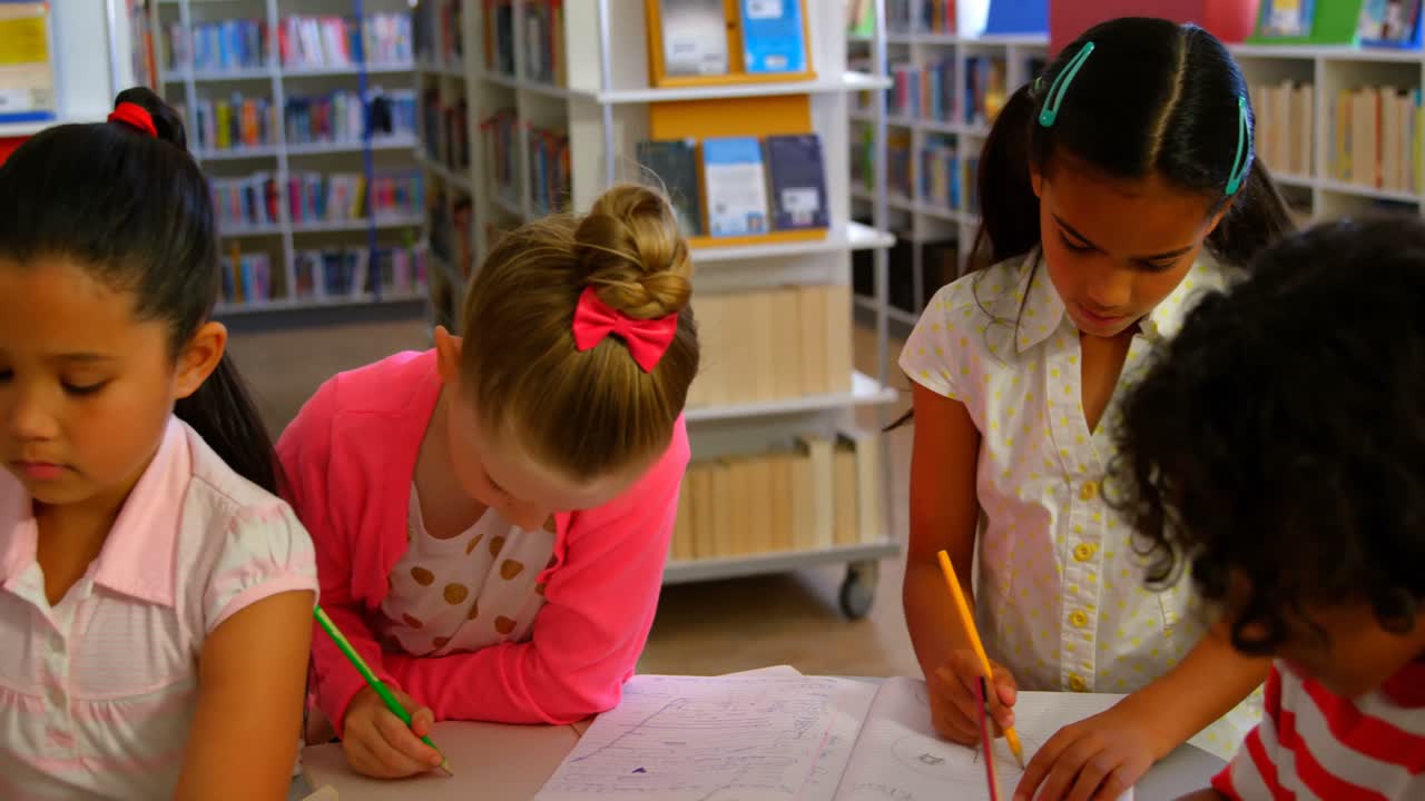 escolares estudiando juntos en una mesa en la biblioteca de la escuela 4k