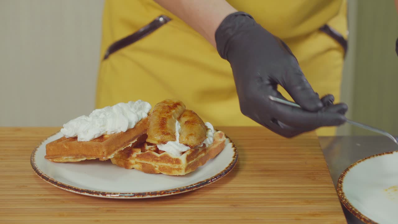 요리사 가 바나나 와 휘프 크림 을 넣은 와플 을 준비 하고 있다