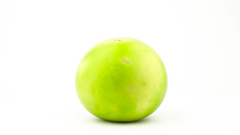 one whole green sweetie fruit. rotating on the turntable. isolated on the white background. close-up. macro.