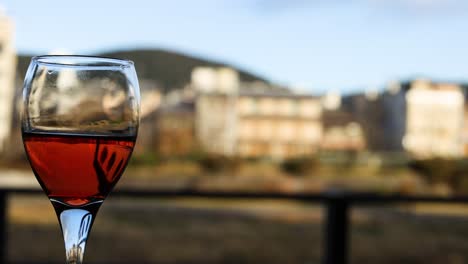 wine glass with red liquid, cityscape in background