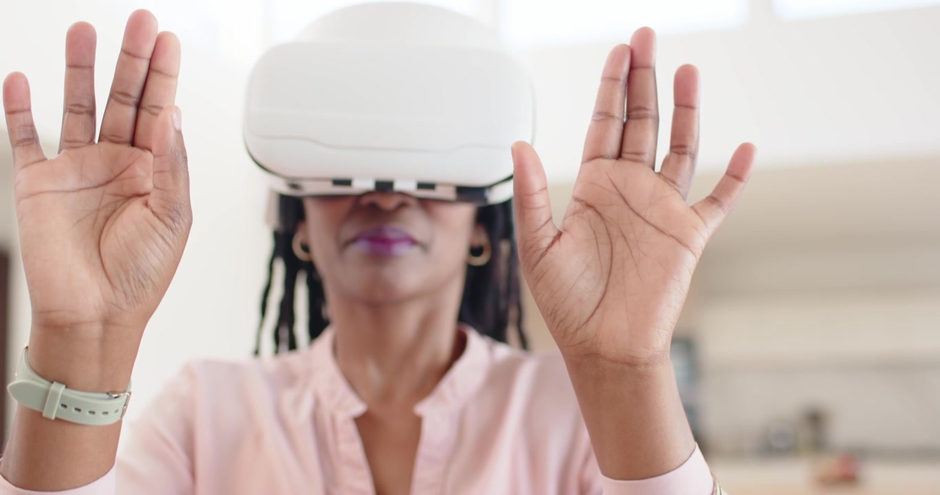 Afroamerikansk kvinde med VR-headset justerer hænderne, kniber for at styre et virtuelt objekt i køkkenet.