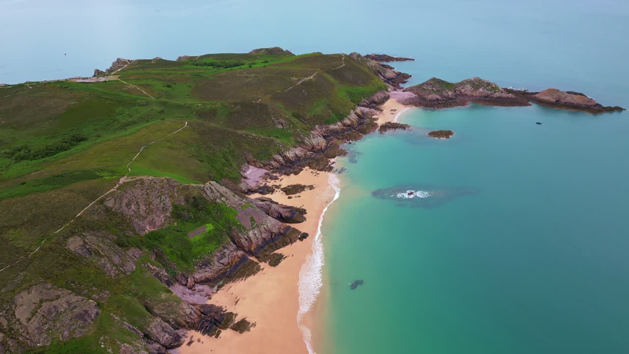 Drone glides sideways revealing the sandy beaches, rocky cliffs, and turquoise waters of Erquy, Brittany, France