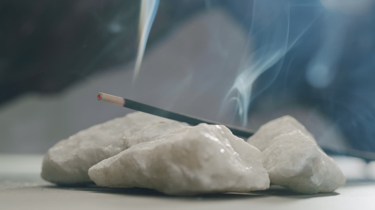 Person holding Palo Santo wood stick in hand, aromatic Palo Santo burning on black background, smoke spreading around, slow motion video clip, high quality 4k close up footage. High quality 4k footage