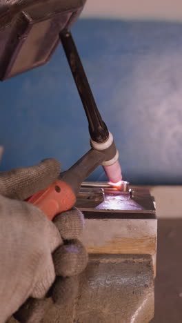soldador en equipo de protección de soldadura de metal con un soldador de tig en un entorno industrial