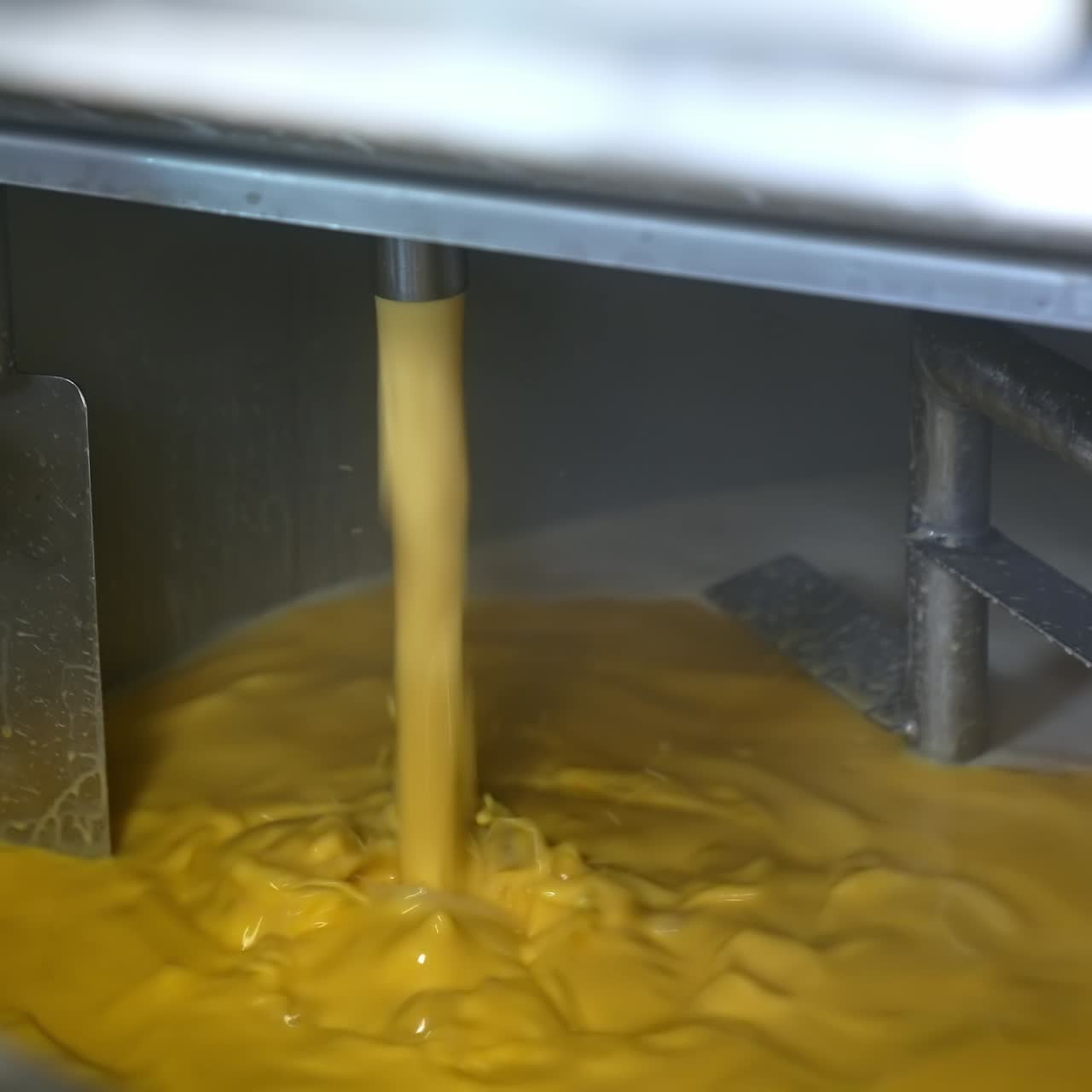 Gul væske hældes i beholder. Produktionslinje for smør eller fløde. Fødevareproduktion. Producent af mejeriprodukter.