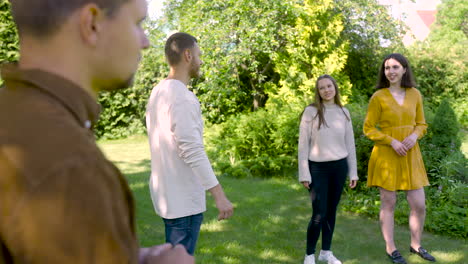 side view of caucasian young man throwing a petanque ball in the park on a sunny day while his friends wait their turns