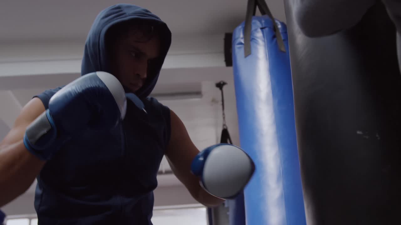 Caucasian man using punchbag in boxing gym