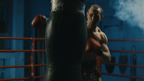 boxer training with punching bag in boxing ring