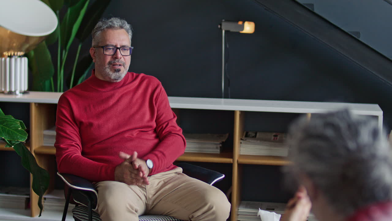 Mid-Aged Man Listening to Female Psychologist during Therapy Session