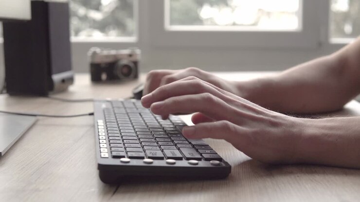 Tippen auf einer Tastatur. Mann tippt auf Computertastatur. Männerhand benutzt Computertastatur und Maus zum Tippen. Freiberuflicher Fotograf arbeitet am Computer.