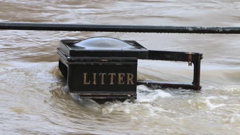 Schnell-Fließendes-Hochwasser-überläuft-Einen-Mülleimer-Und-Ein-Geländer