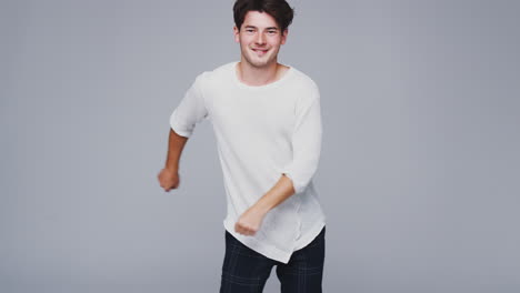 wide angle studio shot of young man against white background dancing and flossing in slow motion