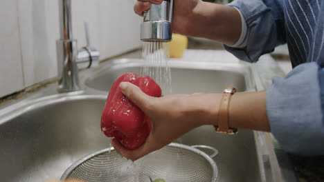 Manos-De-Una-Mujer-Birracial-Lavando-Pimiento-Rojo-En-El-Fregadero-De-La-Cocina,-Cámara-Lenta