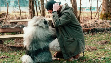 Amorosamente,-El-Joven-Rubio-Se-Inclina-Hacia-Su-Esponjoso-Spitz-De-Lobo-De-Color-Gris-Mientras-Sostiene-Sus-Patas