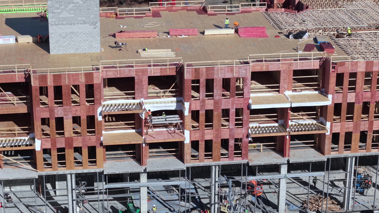 Machinery And Workers Working On An Apartment Building Construction Site In America, Sliding Aerial Shot.
