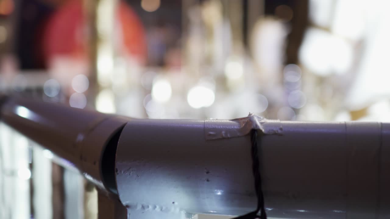 Spinning carousel in the amusement park at night. The focus is on the front and the background is blurred. The focus is on the metal railings. The carousel is on the right.