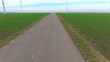 Straße-Entlang-Der-Grünen-Wiese-Mit-Windkraftanlagen