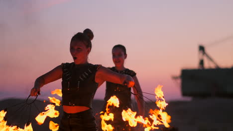 fire dancers against sunset. a young woman poses with her fire hoop against the sunset during her dance performance