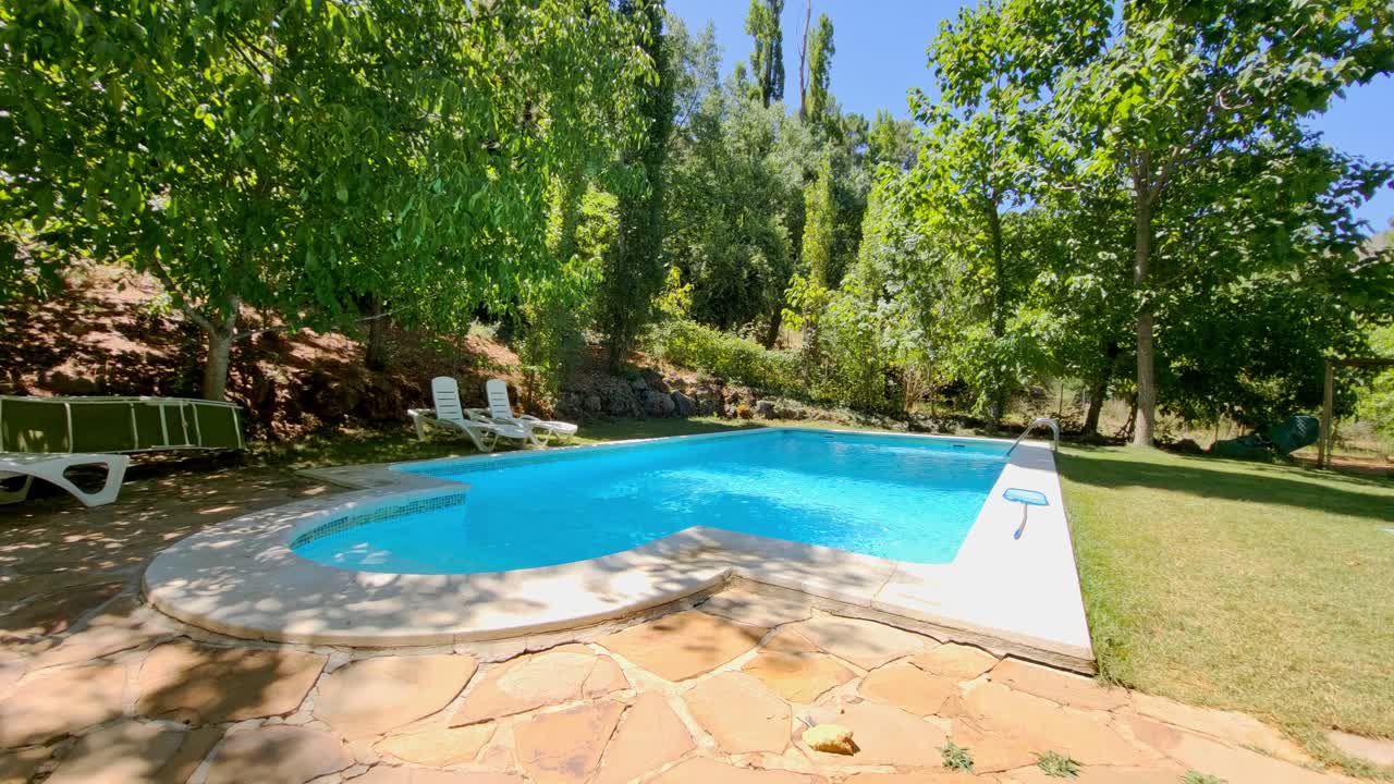 Vacation villas. Lifestyle. Pool between the trees. Colorful blue pool next to the forest and grass area. Summer vacation. Spain
